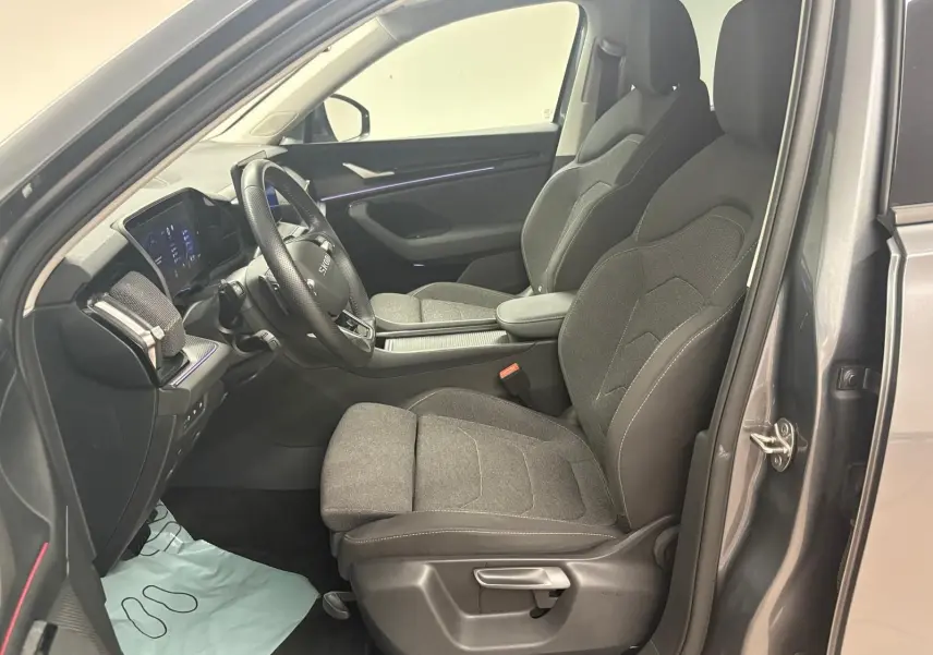 Vue intérieure côté conducteur du Skoda Kodiaq gris graphite 2025, montrant les sièges avant et le tableau de bord moderne.