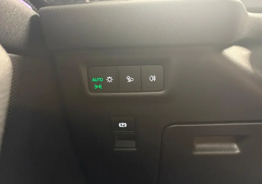 Détail intérieur du tableau de bord côté gauche du Skoda Kodiaq gris graphite, avec commandes d’éclairage et frein à main électrique.