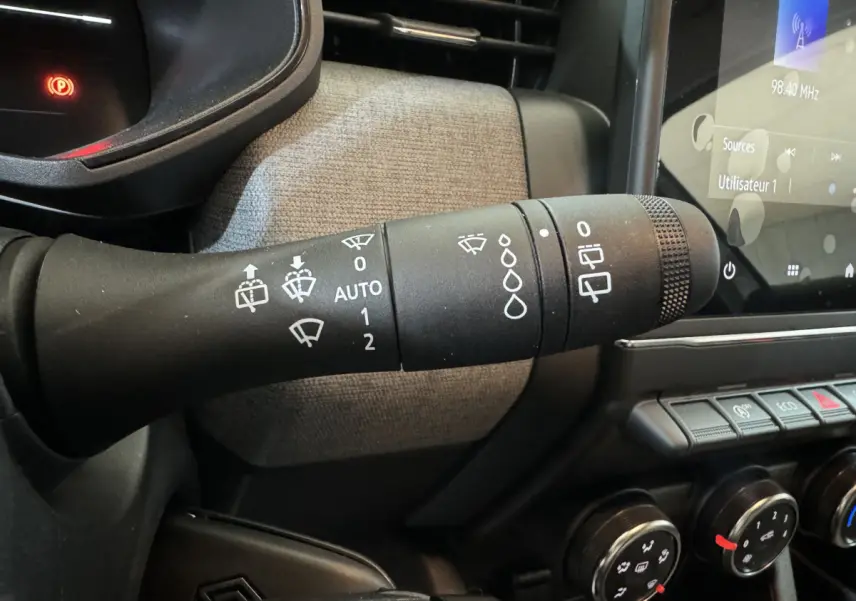 Gros plan sur la commande des essuie-glaces à gauche du volant dans l'habitacle de la Renault Clio gris clair 2025.