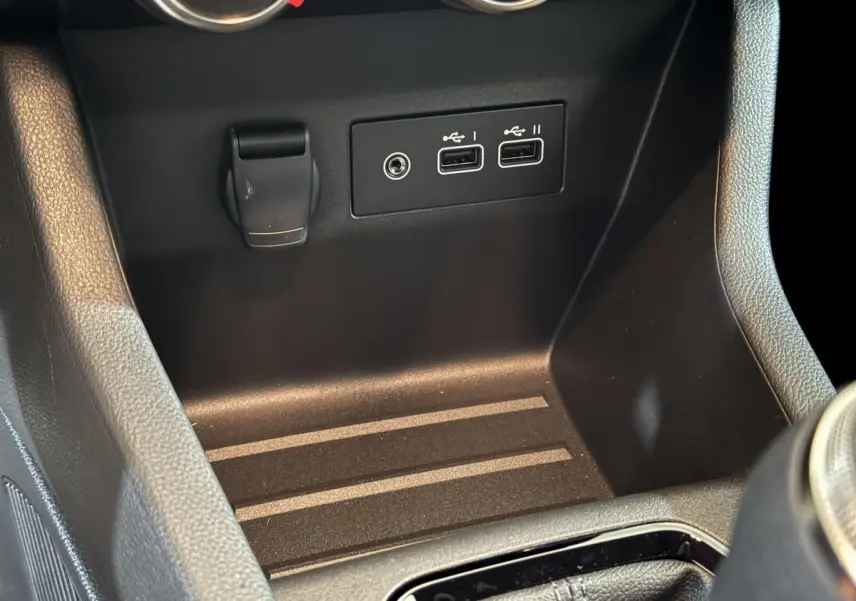 Vue rapprochée de la console centrale noire de la Renault Clio 2025 avec ports USB et prise 12V visibles.