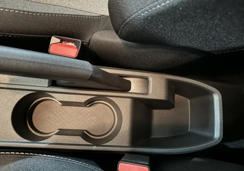 Gros plan sur la console centrale noire de la Renault Clio Evolution Blue dCi 100 avec frein à main manuel et porte-gobelets.