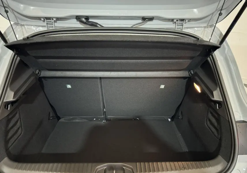 Coffre ouvert d'une Renault Clio gris clair 2025, vue arrière montrant l'espace de chargement vide et la tablette amovible.