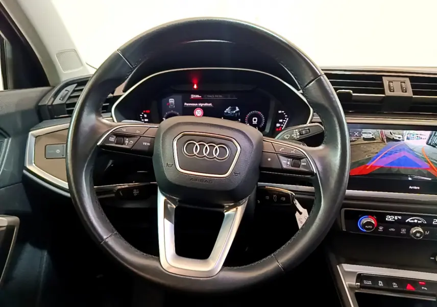 Vue intérieure centrée sur le volant cuir noir de l'Audi Q3 35 TDI 2021 avec tableau de bord digital et écran tactile.
