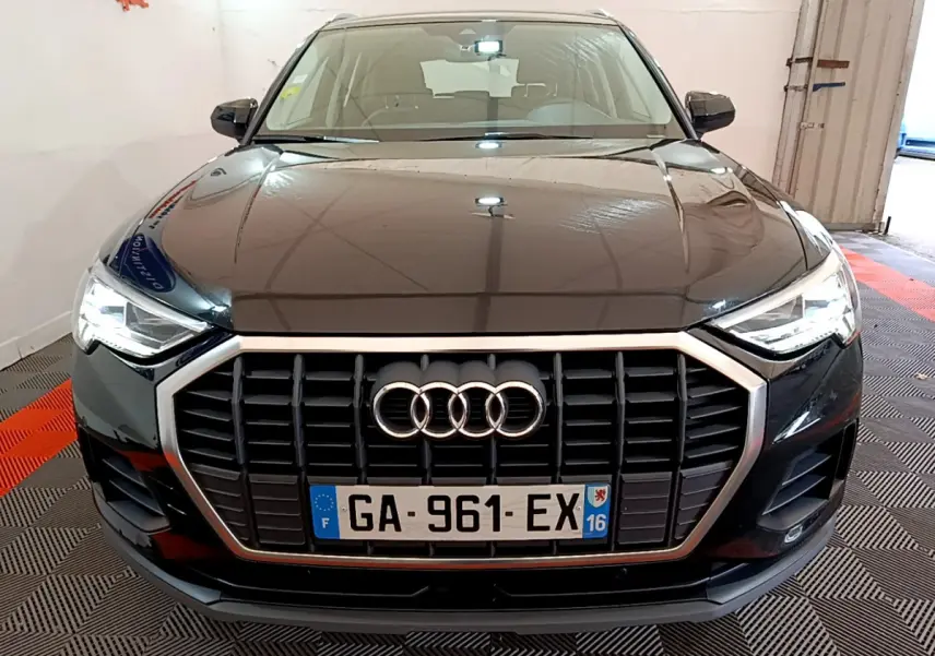 Vue frontale d'un Audi Q3 noir 2021 avec calandre hexagonale et phares LED allumés dans un garage.