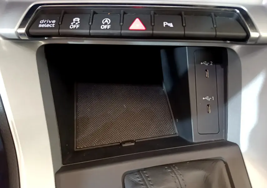 Vue rapprochée de la console centrale noire de l'Audi Q3 35 TDI 2021 avec boutons de contrôle et ports USB visibles.