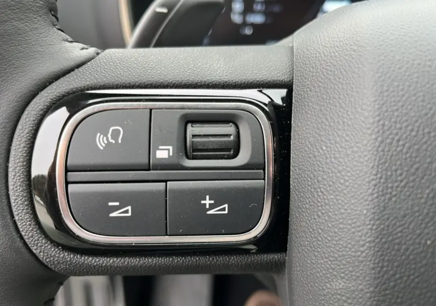 Gros plan sur les commandes noires du volant cuir multifonctions du Citroën C5 Aircross Hybrid 145, finition Eclipse Blue.