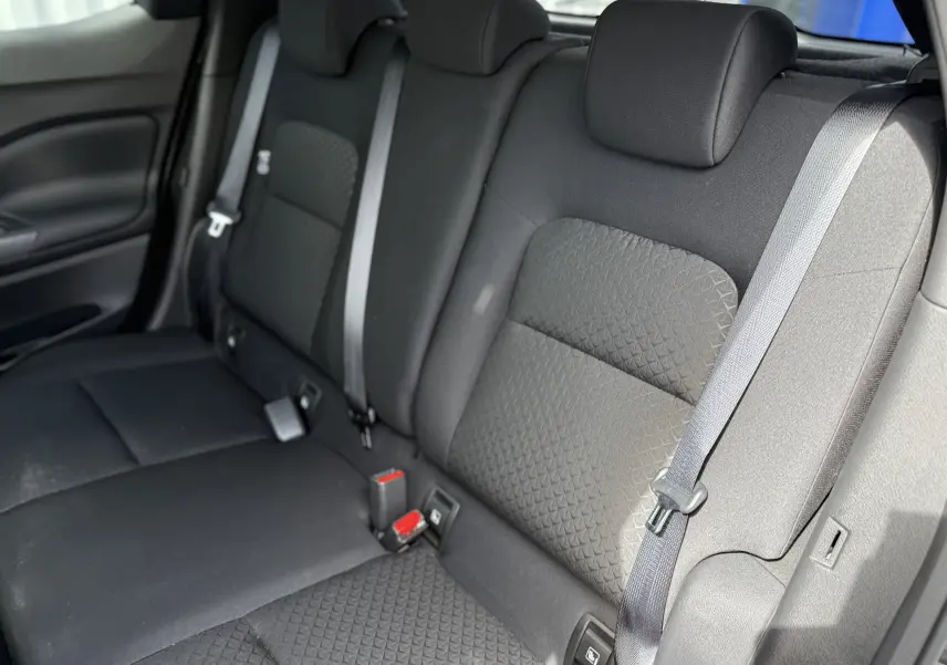 Vue intérieure du siège arrière droit du Nissan Juke Hybrid 2025, tissu gris foncé avec ceinture de sécurité visible.