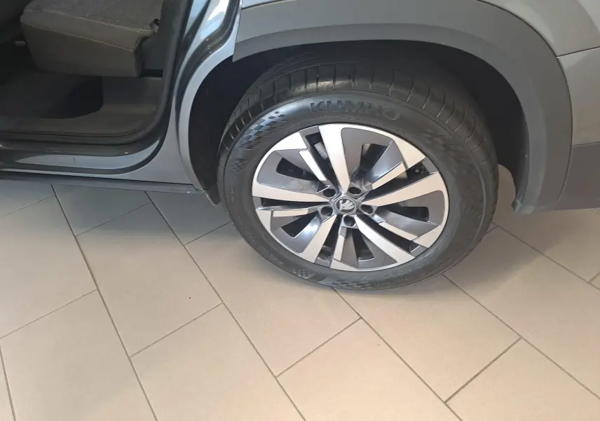 Gros plan sur la roue avant droite du Skoda Kodiaq gris graphite 2025 avec porte arrière ouverte et jante alu bicolore.