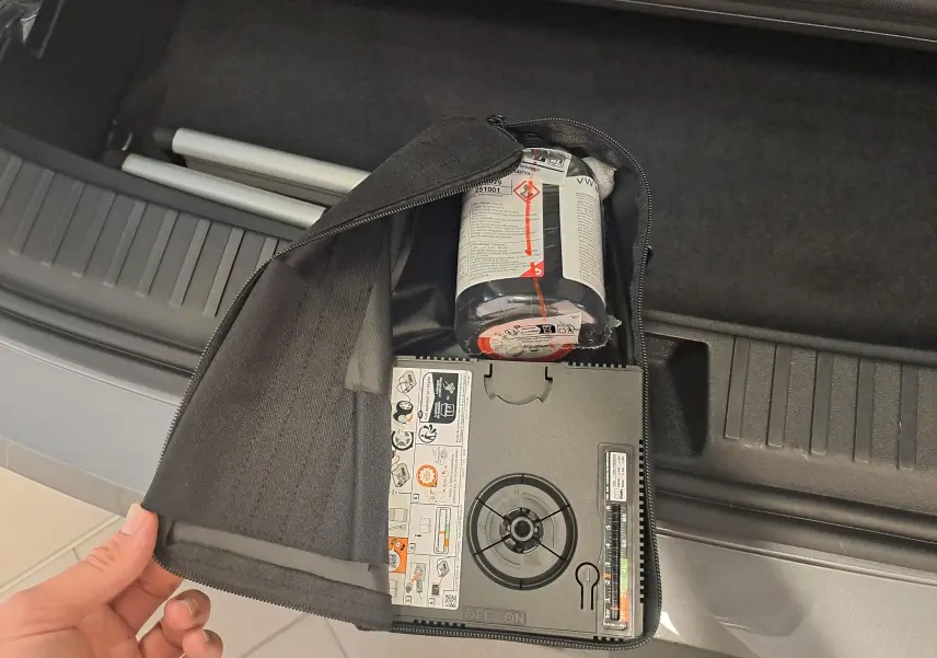 Vue rapprochée du coffre d’un Skoda Kodiaq gris graphite 2025, montrant un kit de réparation pneus dans un sac noir.