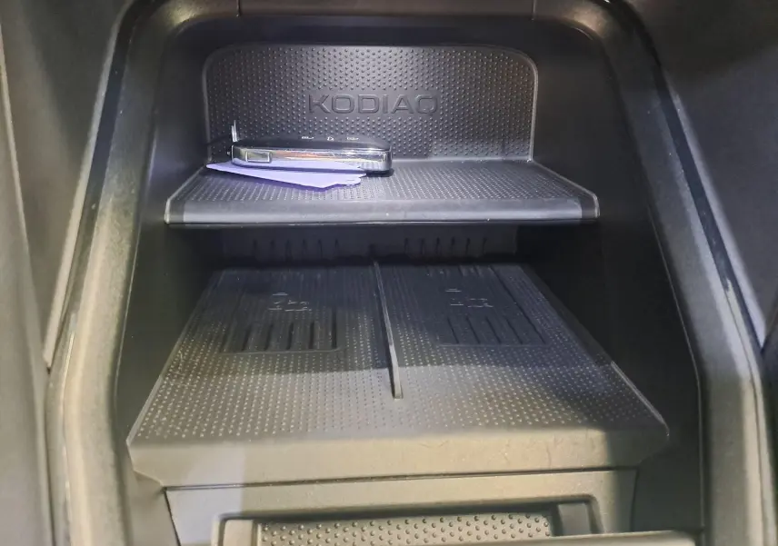 Gros plan intérieur sur le rangement central noir avec logo KODIAQ et clé de voiture posée, dans un Skoda Kodiaq gris graphite 2025.