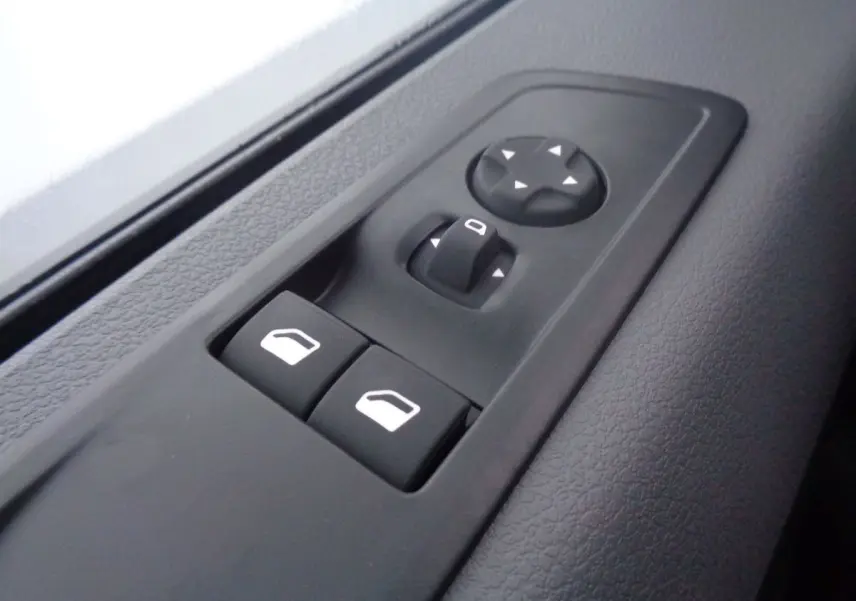 Gros plan sur les commandes de lève-vitres et réglage des rétroviseurs côté conducteur du Peugeot Expert Fourgon noir métal 2022.