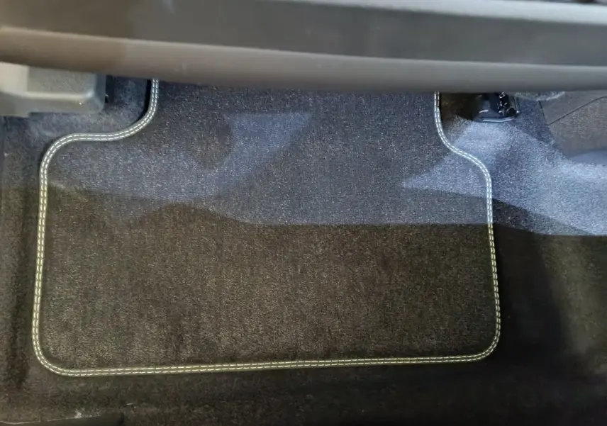 Tapis de sol noir avec surpiqûres blanches dans l'habitacle du Peugeot 3008 gris foncé 2025, côté passager.