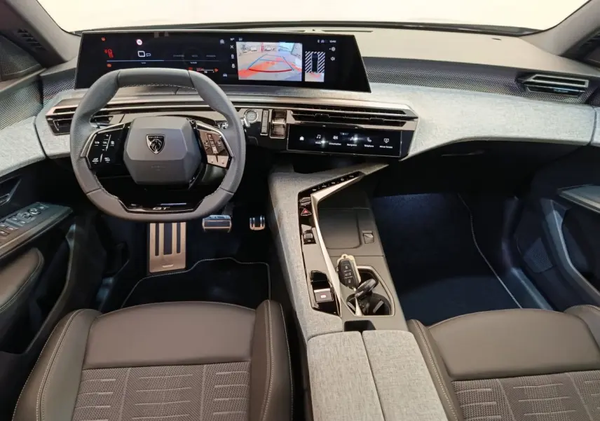 Intérieur du Peugeot 3008 1.2 Hybrid GT 2025, vue du poste de conduite avec volant cuir et grand écran tactile.