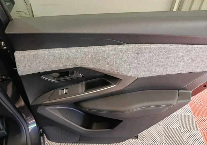 Porte côté gauche intérieur du Peugeot 3008 gris foncé, avec garniture tissu clair et accoudoir en cuir noir.