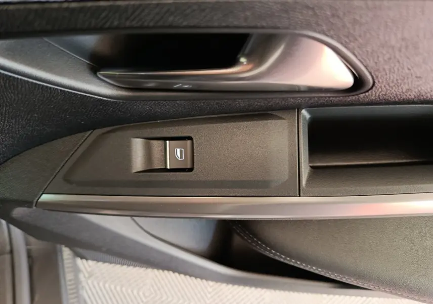 Détail de la poignée intérieure et bouton de lève-vitre côté gauche d'un Peugeot 3008 gris foncé 2025.
