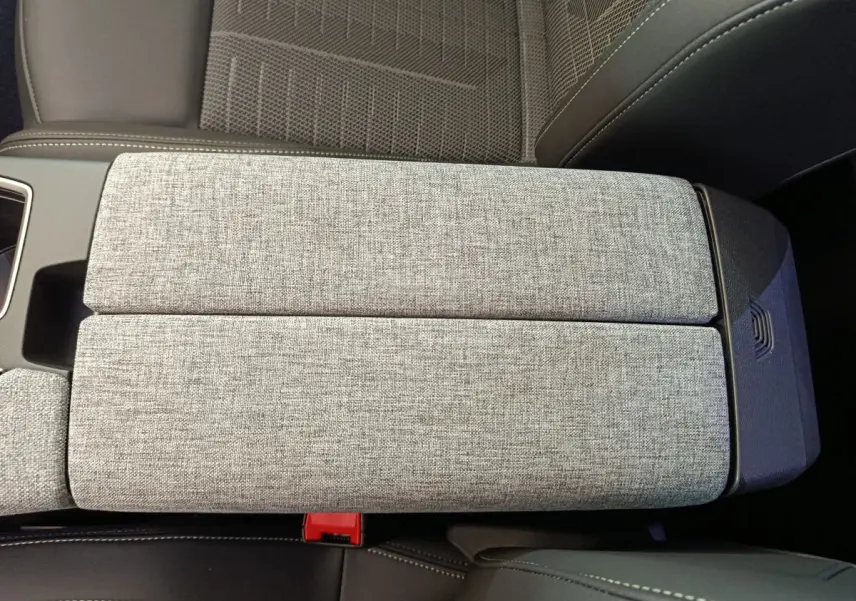 Détail de l'accoudoir central gris clair en tissu et cuir dans l'habitacle du Peugeot 3008 1.2 HYBRID 145 GT 2025.