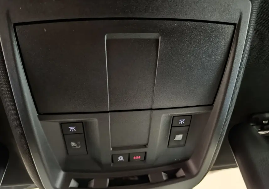 Vue rapprochée du panneau de commandes au plafond intérieur du Peugeot 3008 gris foncé, avec bouton SOS et éclairage.