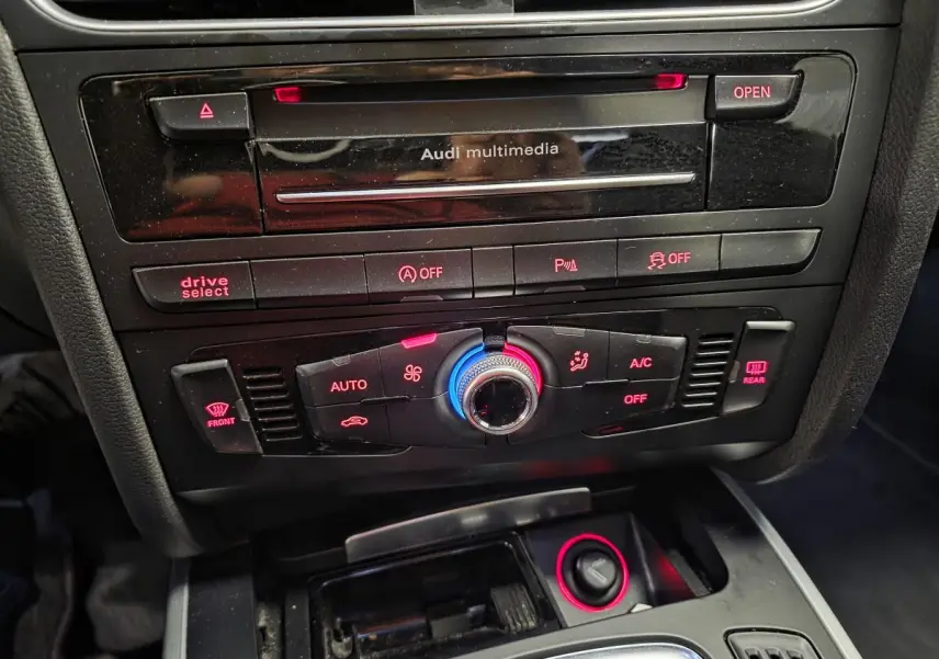 Vue rapprochée de la console centrale noire de l'Audi A5 Cabriolet S Line avec commandes climatisation et lecteur CD Audi multimedia.