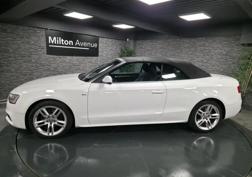 Audi A5 Cabriolet blanc vue de profil côté gauche avec capote noire et jantes sport 5 branches doubles.