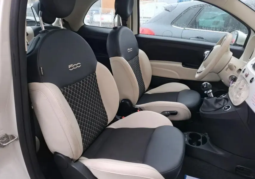 Vue intérieure côté gauche de la FIAT 500 2022 blanche, sièges bi-ton noir et beige avec logo 500 brodé.