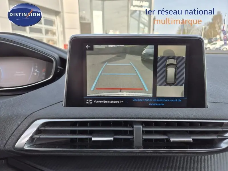 Écran tactile du tableau de bord du Peugeot 3008 blanc nacré affichant la caméra de recul et l'aide au stationnement.