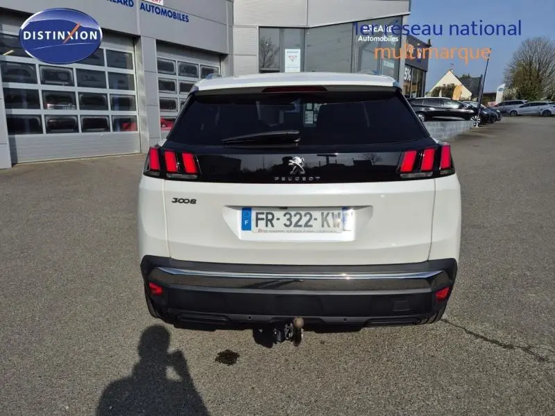 Vue arrière d'un Peugeot 3008 blanc nacré avec feux arrière à griffes rouges et attelage de remorque visible.