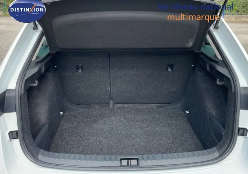 Coffre ouvert d'une Skoda Scala blanc glacier, vue arrière montrant l'espace de chargement vide et tapissé de moquette grise.