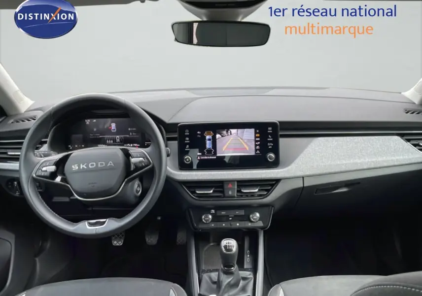 Vue intérieure frontale du tableau de bord gris clair et noir de la Skoda Scala 2025 avec volant cuir et boîte manuelle.