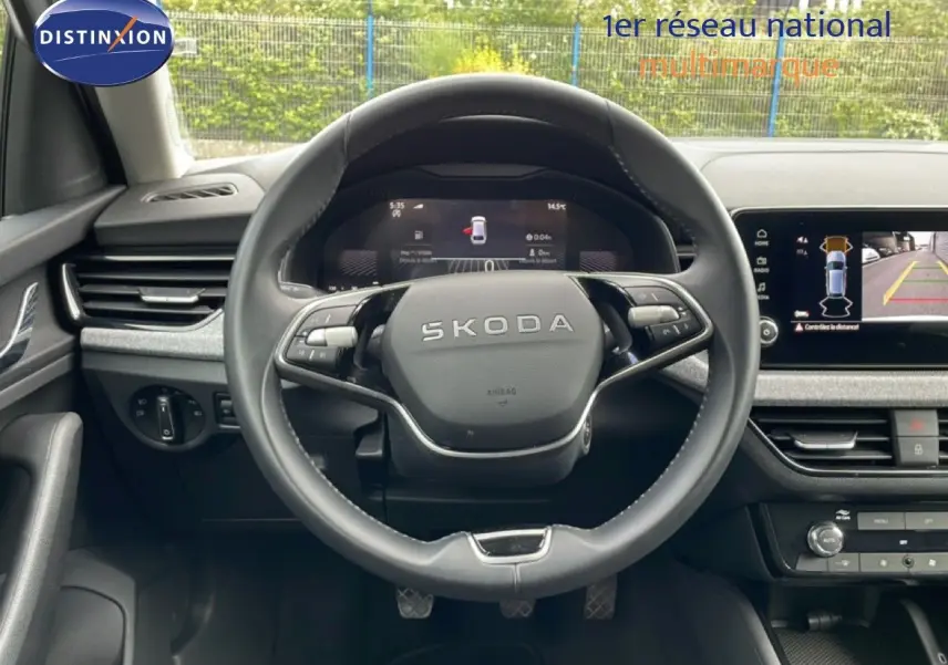 Vue intérieure centrée sur le volant SKODA avec tableau de bord numérique et écran multimédia affichant la caméra 360°