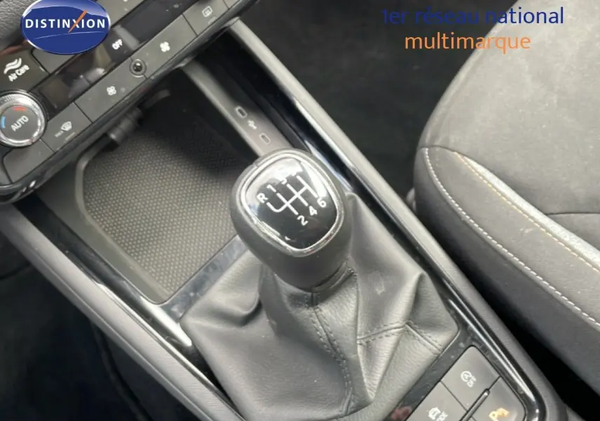 Gros plan sur le levier de vitesses manuel de la Skoda Scala 2025, intérieur tissu gris noir avec console centrale noire brillante.