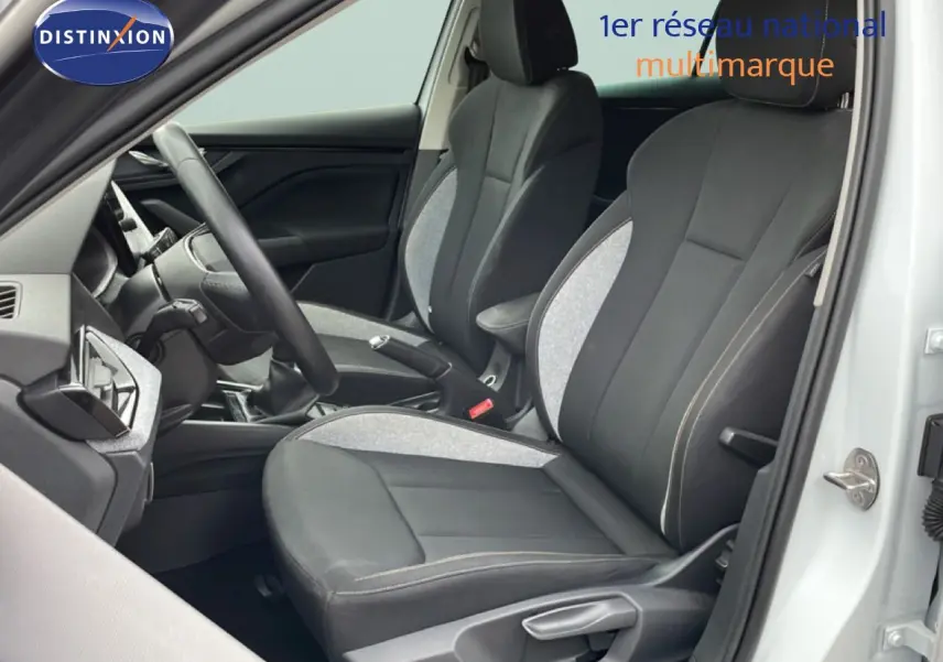 Vue intérieure côté conducteur de la Skoda Scala blanc glacier, sièges tissu gris et noir avec volant multifonction.