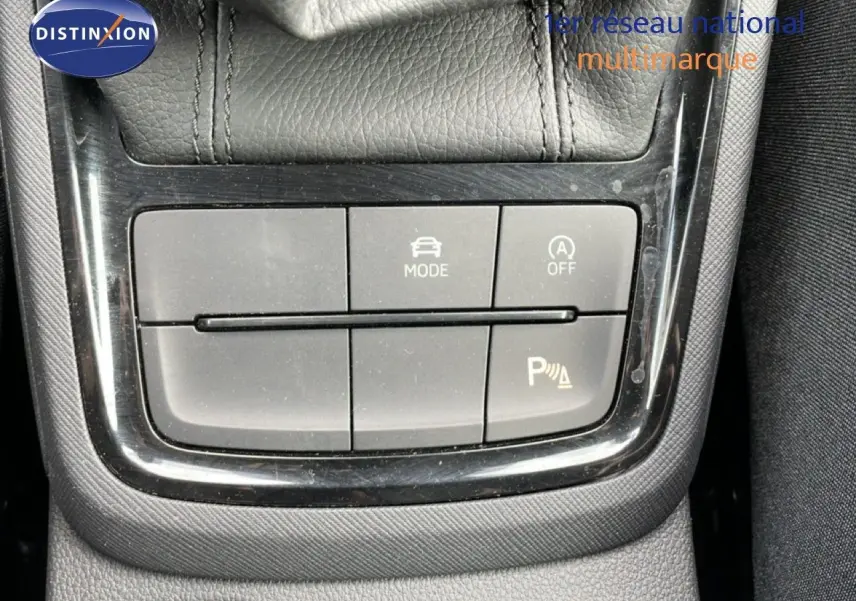 Gros plan sur les boutons de commande du mode de conduite et de l'aide au stationnement dans une Skoda Scala blanche.