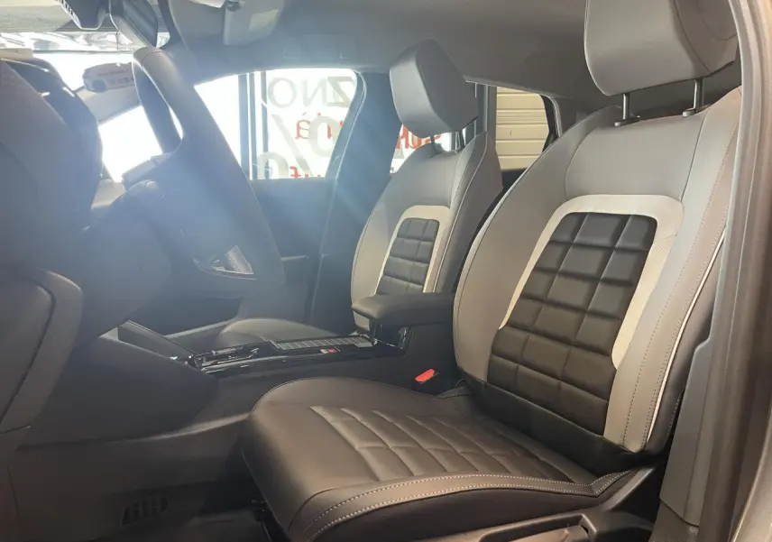 Vue intérieure côté conducteur de la Citroën C4 2026 avec sièges bi-ton gris et noir et accoudoir central.