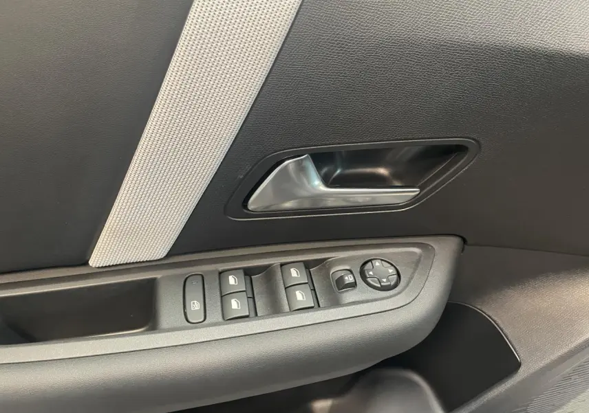 Gros plan sur la porte côté gauche de la Citroën C4 gris, avec commandes de vitres et poignée intérieure argentée.