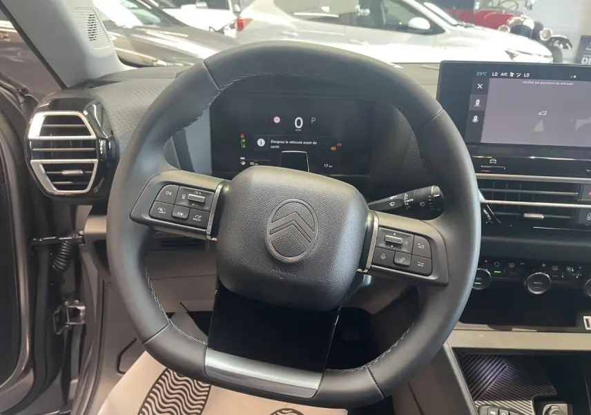 Vue intérieure centrée sur le volant cuir noir de la Citroën C4 avec tableau de bord digital et écran tactile.