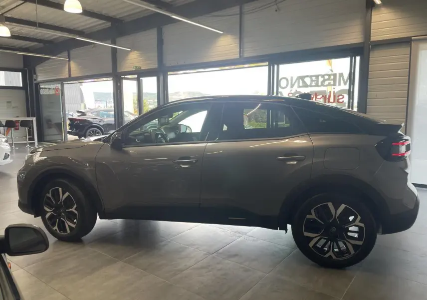 Vue latérale droite d'une Citroën C4 gris métallisé avec toit bi-ton noir Perla Nera en showroom.
