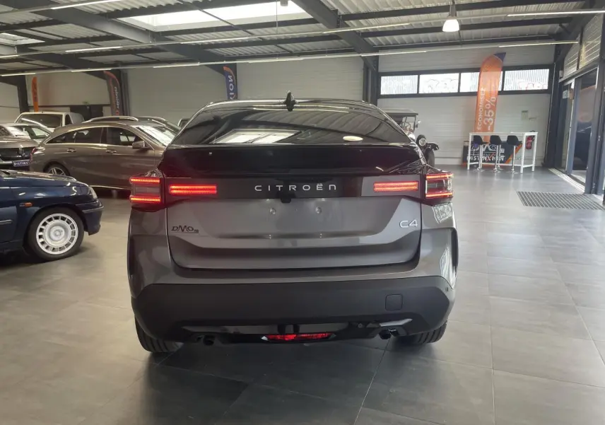 Vue arrière d'une Citroën C4 grise avec feux LED allumés dans un showroom lumineux.