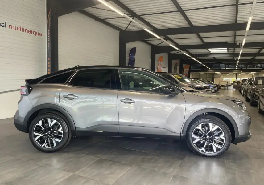 Profil droit d'une Citroën C4 gris métallisé avec toit noir et jantes alliage 18 pouces en intérieur showroom.