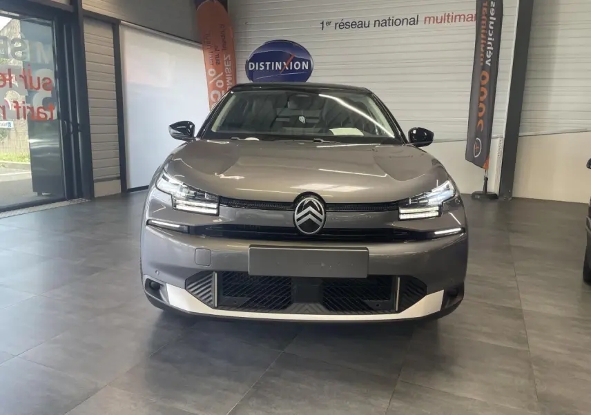 Vue frontale d'une Citroën C4 gris métallisé avec toit noir Perla Nera, dans un showroom intérieur.
