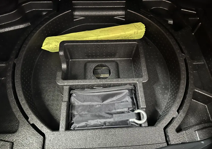 Compartiment de rangement sous le coffre du DS4 2024 noir Perla Nera avec kit de secours et outil jaune visible.