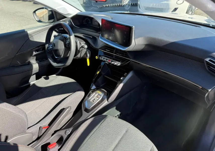 Vue intérieure côté conducteur de la Peugeot 208 gris Artense, avec tableau de bord moderne et écran tactile central.