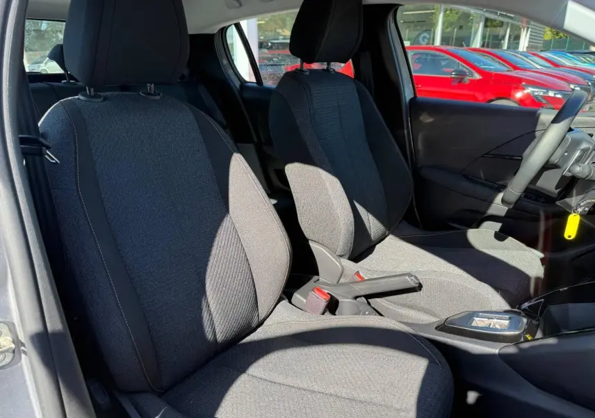 Vue intérieure des sièges avant en tissu gris RENZO avec surpiqûres Orange Sunrise d'une Peugeot 208 1.2 Hybrid 2025.