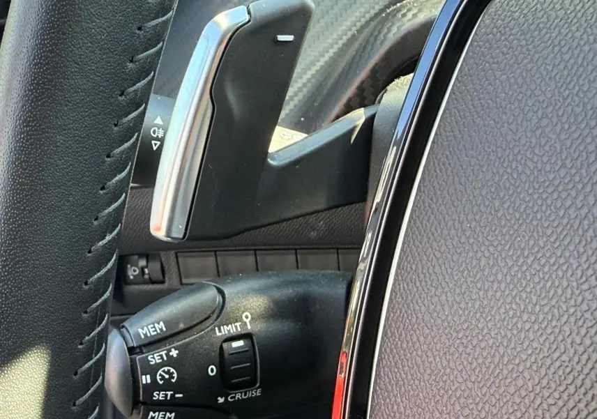 Gros plan sur la commande de régulateur de vitesse à gauche du volant, intérieur tissu gris avec surpiqûres orange.