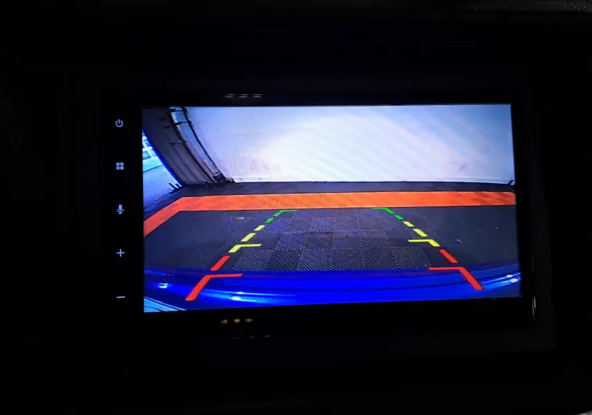 Vue caméra de recul montrant le pare-chocs bleu d'une Aixam Ambition 0.5 City GTO 2025 avec repères de stationnement colorés.