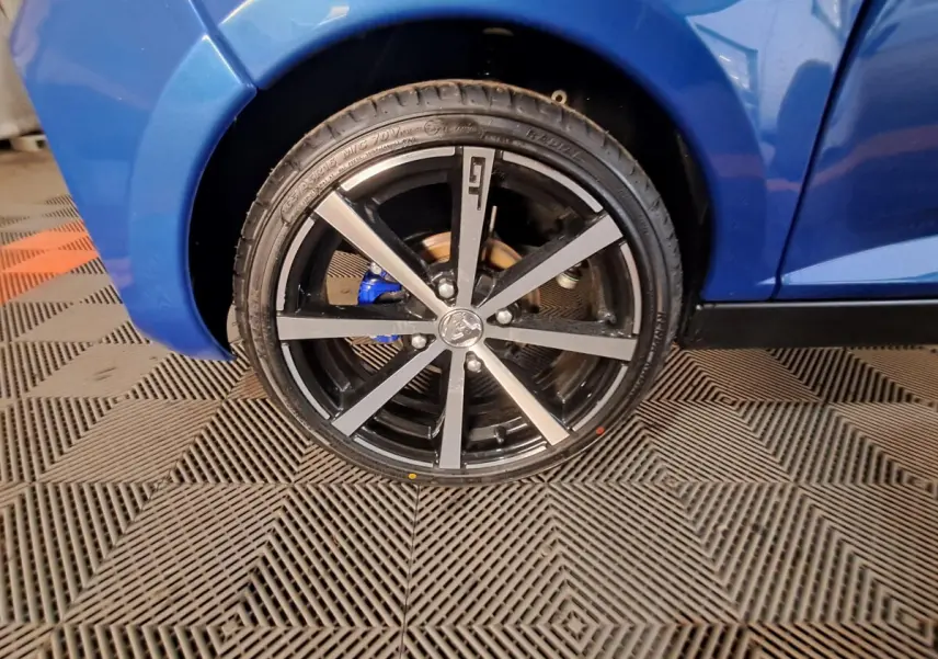 Gros plan sur la roue avant droite d'une Aixam Ambition 2025 bleu avec jante noire et détails gris métallisé