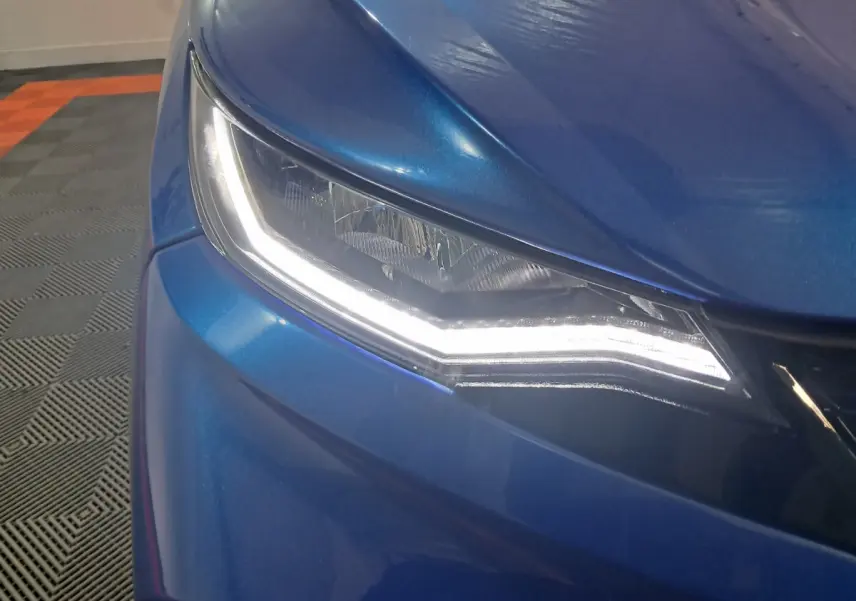 Gros plan sur le phare avant gauche bleu de l'AIXAM AMBITION 0.5 CITY GTO 2025 avec éclairage LED distinctif.