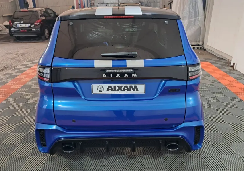 Vue arrière d'une Aixam Ambition bleu 2025 avec bandes blanches et logo GTO dans un garage.