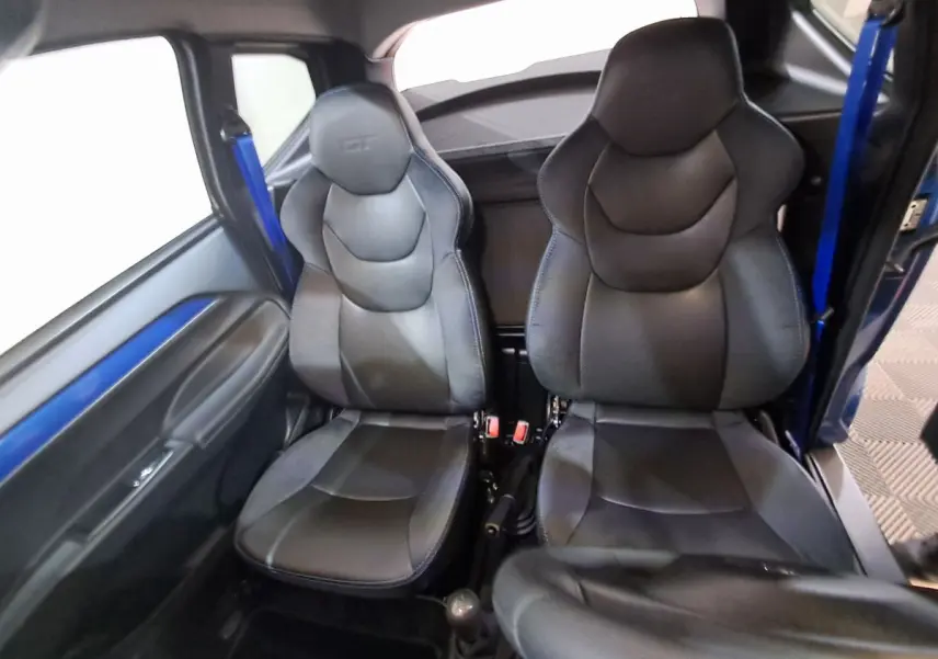 Intérieur de l'AIXAM AMBITION 2025 montrant les sièges sport noirs avec ceinture bleue côté gauche.