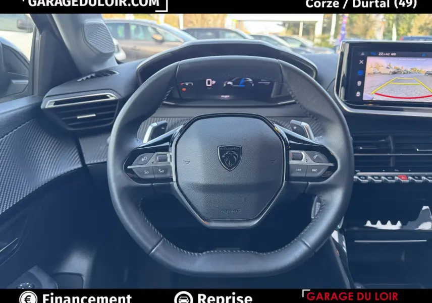 Vue intérieure centrée sur le volant cuir noir multifonctions de la Peugeot 208 Hybrid gris clair, avec tableau de bord numérique.