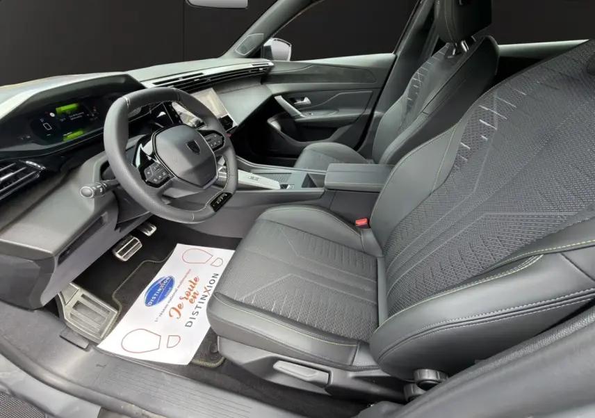 Intérieur avant droit de la Peugeot 308 gris clair 2026, avec sièges tissu et cuir, volant multifonction et tableau de bord numérique.